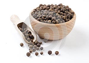 Allspice  in wooden bowl and scoop isolated on white background. Spices and food ingredients