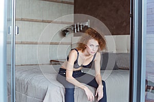 Alluring attractive young woman sitting on bed in bedroom