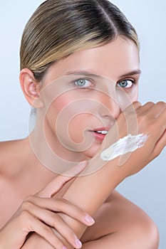 Alluring beautiful woman applying moisturizer cream on her hand for perfect skin