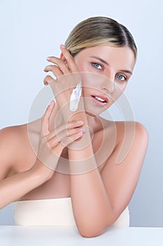 Alluring beautiful woman applying moisturizer cream on her hand for perfect skin