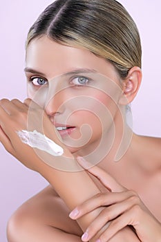 Alluring beautiful woman applying moisturizer cream on her hand for perfect skin