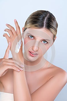 Alluring beautiful woman applying moisturizer cream on her hand for perfect skin