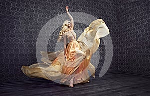 Alluring blond woman dancing in a stylish gown