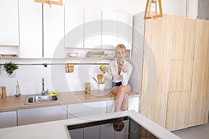 Alluring female holding cell phone and eating apple, sitting on