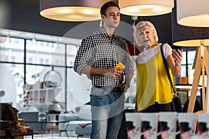 Alluring old fashionable lady selecting lamps with handsome tall gentlemen