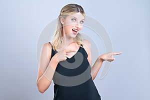 Alluring portrait of woman pointing finger side way in isolated background.