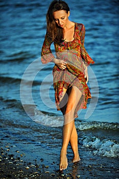 Alluring woman posing on the beach in floral transparent dress.