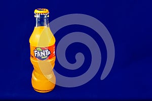 Almeria, Spain; November 25th, 2021: 200ml Orange flavoured Fanta bottle, Classic glass bottle with metal cap isolated on blue.