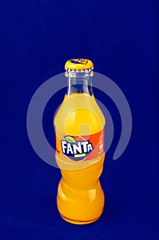 Almeria, Spain; November 25th, 2021: 200ml Orange flavoured Fanta bottle, Classic glass bottle with metal cap isolated on blue.