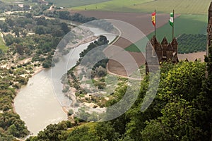 Almodovar Del Rio medieval castle with flags of Spain and Andalusia above Guadalquivir river