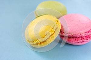 Almond cookies on blue background with copy space. Pink, yellow and green macaroons