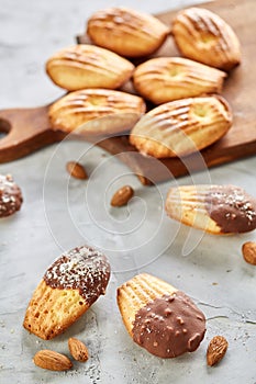 Almond cookies and raw almonds on wooden cutting board over white background, close-up, selective focus.