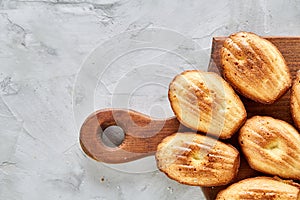 Almond cookies and raw almonds on wooden cutting board over white background, close-up, selective focus.