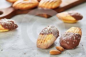 Almond cookies and raw almonds on wooden cutting board over white background, close-up, selective focus.