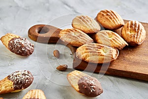 Almond cookies and raw almonds on wooden cutting board over white background, close-up, selective focus.