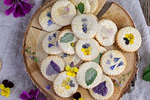 almond floral cookies with edible flowers as violets, speedwell, chamomile, mallow or lemon balm and mint leaves