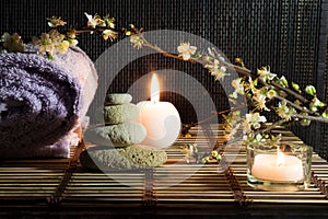 Almond flowers with towel, candles, white stones on bamboo mat
