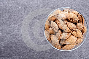 almond on glass plate on dark grey linen napkin background, top view on right side