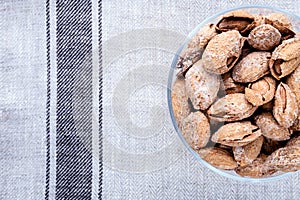 almond on glass plate on light grey linen napkin background, top view on right side