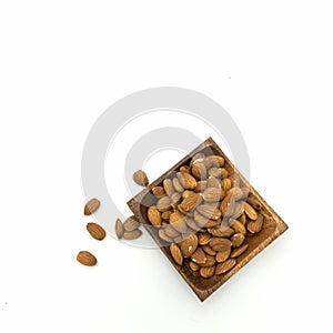 Almond kernels lie in and next to a wooden square saucer