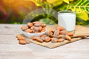 Almond milk and Almonds nuts on white bowl with green leaf on sack background, Delicious sweet almonds on the wooden table ,