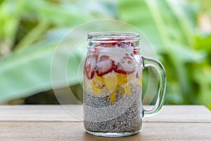 Almond milk chia pudding with fresh strawberries and mango in a glass jar mug. Vegan raw breakfast. Chia seeds and fresh cut