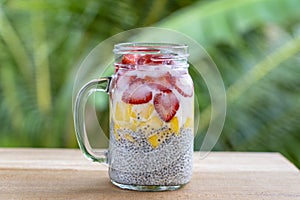 Almond milk chia pudding with fresh strawberries and mango in a glass jar mug. Vegan raw breakfast. Chia seeds and fresh cut