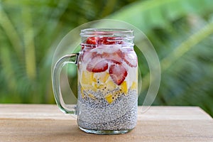 Almond milk chia pudding with fresh strawberries and mango in a glass jar mug. Vegan raw breakfast. Chia seeds and fresh cut