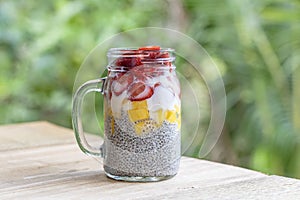 Almond milk chia pudding with fresh strawberries and mango in a glass jar mug. Vegan raw breakfast. Chia seeds and fresh cut