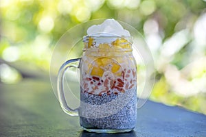 Almond milk chia pudding with fresh yellow mango and red goji berries in a glass jar mug. Vegan raw breakfast. Chia seeds and