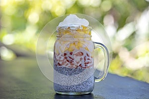 Almond milk chia pudding with fresh yellow mango and red goji berries in a glass jar mug. Vegan raw breakfast. Chia seeds and