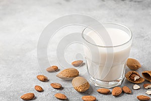 Almond milk in a glass with almond nuts on concrete background. Vegan dairy free plant milk