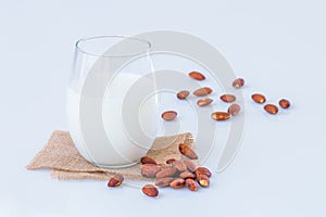 Almond milk in a glass with almond seeds on marble table.