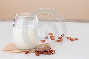 Almond milk in a glass with almond seeds on marble table.