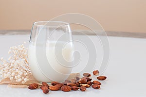 Almond milk in a glass with almond seeds on marble table.