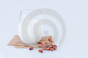 Almond milk in a glass with almond seeds on marble table.