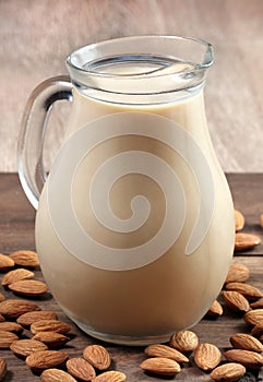 Almond milk in a glass jug on a wooden table.