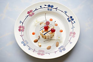almond mousse with slivered almonds and cherry on porcelain plate
