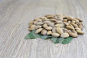 Almond nut on green leaf on wood background