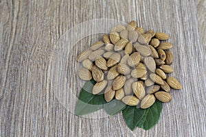 Almond nut on green leaf on wood background