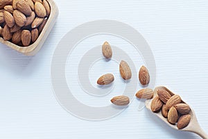 Almond nut in wood bowl and green leaf on wooden table background