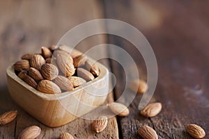 Almond nut in wood bowl on wooden table with green leaf background