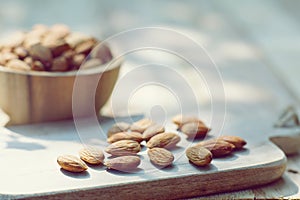 Almond nut in wooden bowl on wood board and table background, copy space