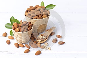 Almond nuts in basket with wood spoon isolated on white wooden background, Almonds are healthiest nuts and one of the best brain