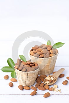 Almond nuts in basket with wood spoon isolated on white wooden background, Almonds are healthiest nuts and one of the best brain