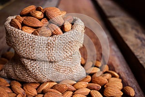 Almond nuts in a burlap bag on wooden background