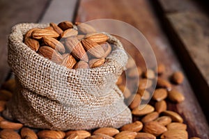 Almond nuts in a burlap bag on wooden background