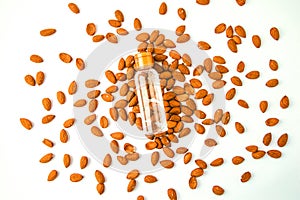 Almond nuts scattered white wooden table, bottles of culinary and cosmetic skincare seed oil