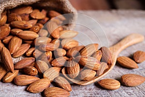 Almond nuts in wooden spoon on rustic background