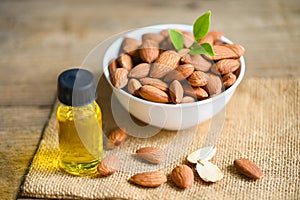 Almond oil and Almonds nuts on bowl, Delicious sweet almonds oil in glass bottle, roasted almond nut for healthy food and snack